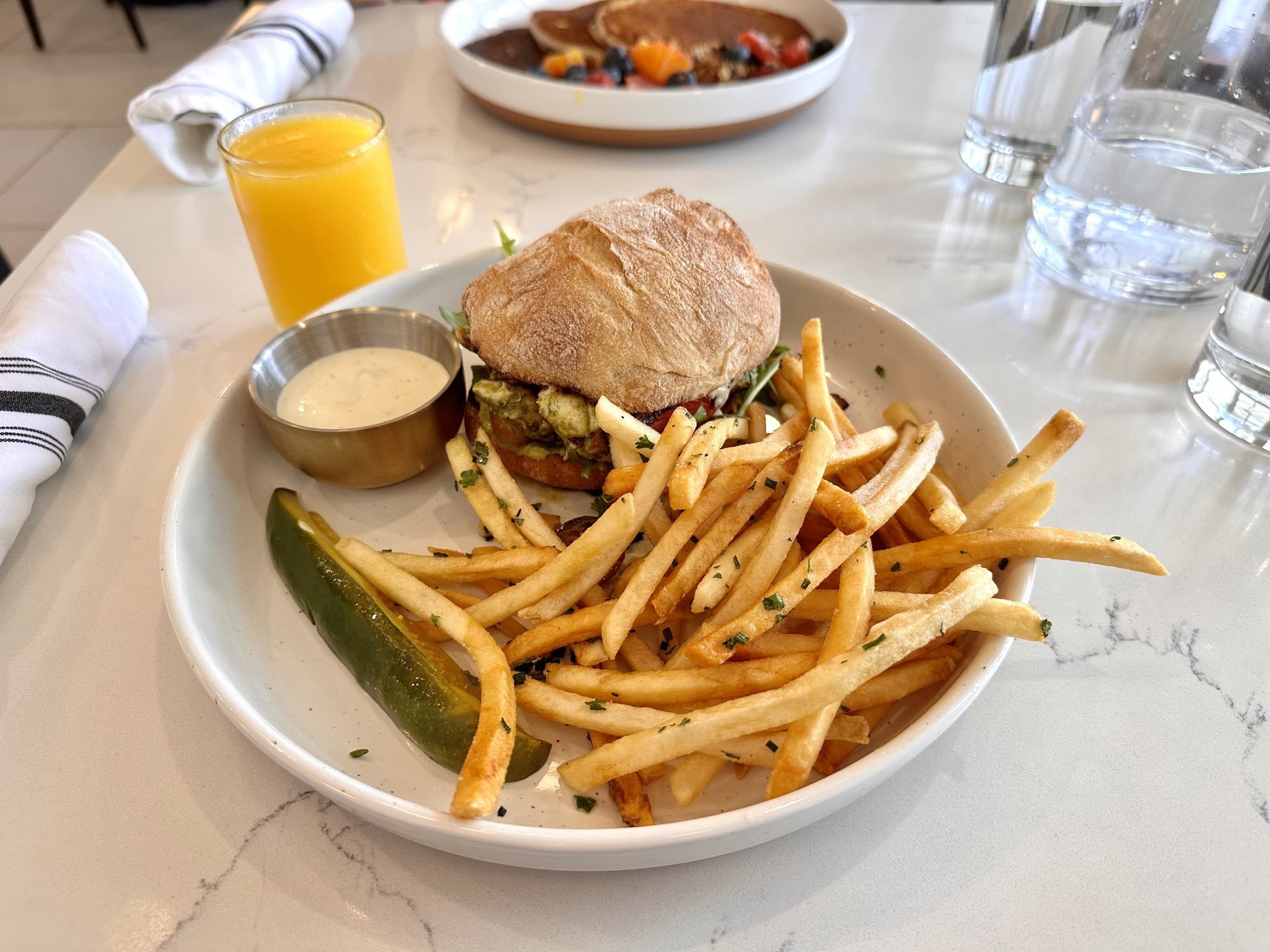 plate with fries and a burger with pickle spear